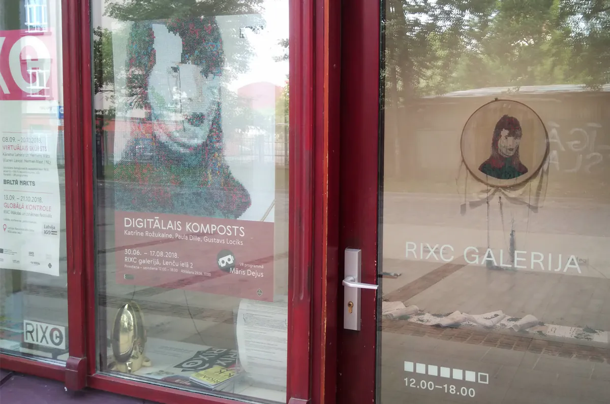 RIXC galerijas skatlogs ar instalācijas plakātu un izšūto portretu